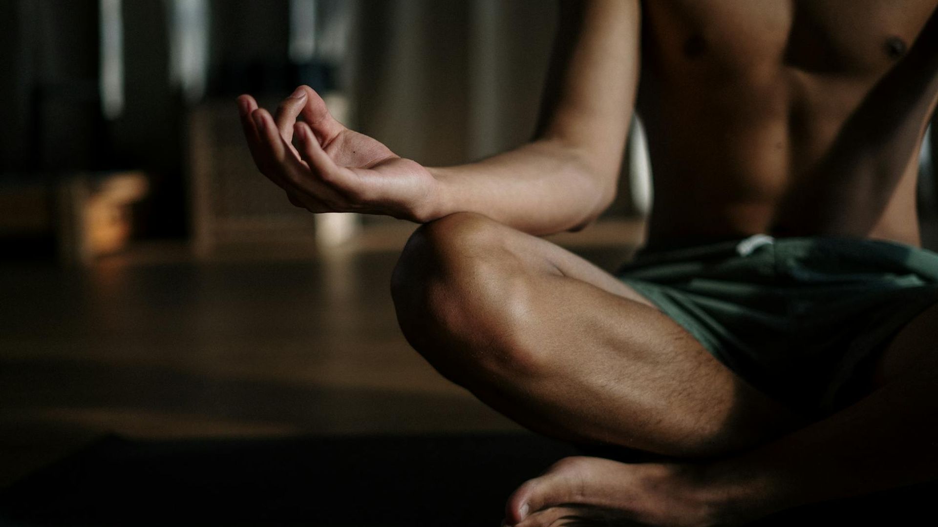 Serene person practicing yoga in a dark studio with neon light